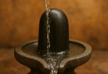 एक भक्त द्वारा पीतल के लोटे से शिवलिंग पर जल अर्पित करते हुए पवित्र दृश्य, जिसमें जल शिवलिंग पर गिरकर नीचे बहता दिखाई दे रहा है।